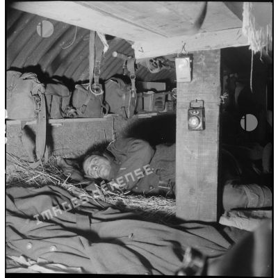 A l'intérieur d'un abri fortifié, un soldat de la 2e armée dort couché dans de la paille.