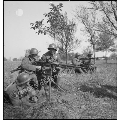 Plan général de soldats qui servent des mitrailleuses Hotchkiss M14, photographiées de profil.