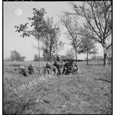 Plan général de soldats qui servent une mitrailleuse Hotchkiss M14 photographiée de profil.