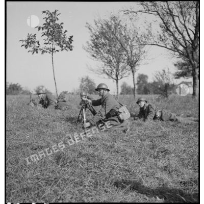Plan général d'un soldat qui sert un mortier de 60 mm M35 photographié de trois quarts avant.