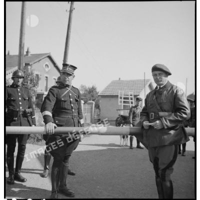 Photographie de groupe de douaniers belges, de soldats français et de civils à un poste-frontière.