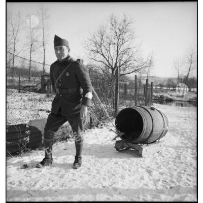 Dans la neige plan général d'un soldat qui tire un tonneau d'eau posé sur un traîneau.