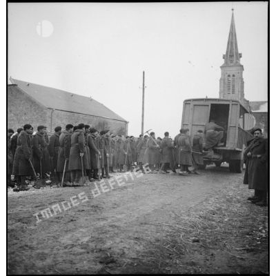 Des soldats de la 2e armée, portant des pelles et des pioches, montent à l'arrière d'un camion.