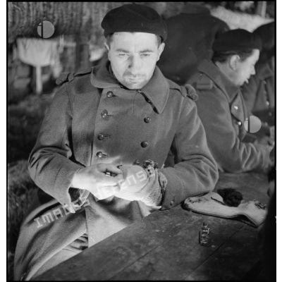 Portrait d'un soldat de la 2e armée qui joue aux cartes à l'intérieur d'un abri de campagne.