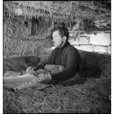 Portrait d'un soldat de la 2e armée assis sur son châlit à l'intérieur d'un abri de campagne.