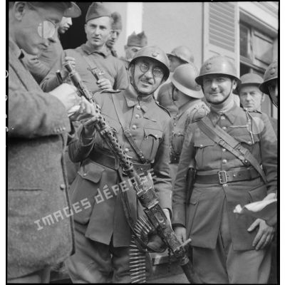 Deux officiers du 151e RI (régiment d'infanterie) présentent une mitrailleuse allemande MG-34 prise à l'ennemi, suite à l'offensive de la Sarre (Allemagne).