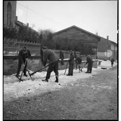 Plan général de soldats qui déblayent de la neige accumulée sur un trottoir.