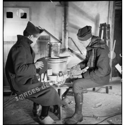 Dans une pièce, photographie de groupe de soldats qui mangent près d'un poêle.