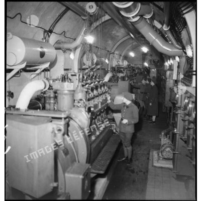 Deux officiers, dont un lieutenant, inspectent l'un des moteurs SMIM de 90 ch qui équipent l'ouvrage de Velosnes.