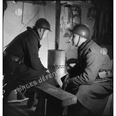 Portrait de groupe de soldats de la 2e armée qui se réchauffent près d'un poêle à l'intérieur d'une casemate.