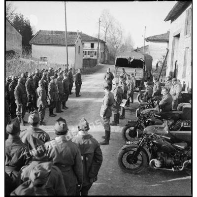 Au matin, plan général d'un rapport d'une unité motocycliste de la 2e armée dans une rue de village.