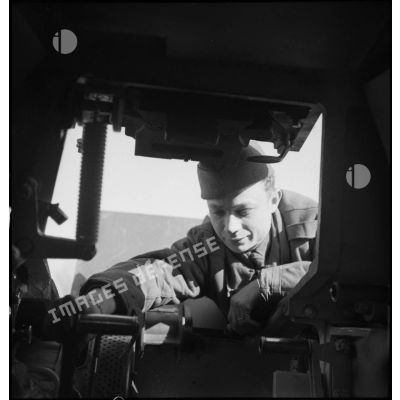 Portrait d'un mécanicien qui se penche à l'intérieur du poste de pilotage d'un Hotchkiss M35/39 H de la 2e armée.