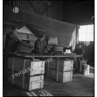 Dans l'atelier de réparation de campagne des soldats travaillent sur la sellerie de véhicule.