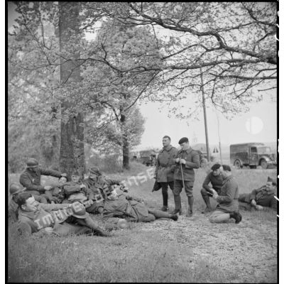 Des soldats et des conducteurs d'une colonne motorisée française se reposent en bordure d'une route.
