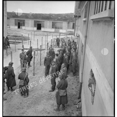Photographie de groupe en plongée de prisonniers allemands rassemblés dans un camp.