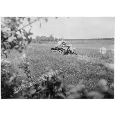Un char Renault R35 est photographié en plan général de trois quarts dos alors qu'il se déplace dans un champ.