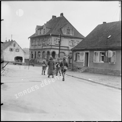 Des cavaliers du 11e GRCA et des fantassins de la 42e DI marchent dans une rue de Lauterbach.