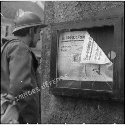Dans une rue de Lauterbach, le portrait d'un soldat qui lit un journal de la Waffen-SS "Das Schwarze Korps".
