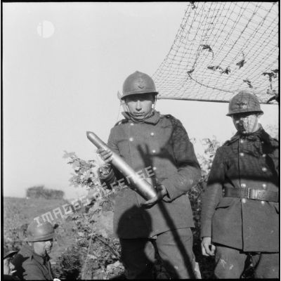 Photographie de groupe d'artilleurs de la 3e armée, l'un d'entre-eux tient en main un obus de 75 mm.