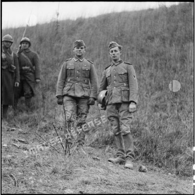 Deux prisonniers allemands ramenés par une patrouille de la 3e armée sont photographiés en pied.