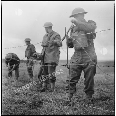 Des soldats britanniques de la 51e DI (BEF) mettent en place des barbelés.