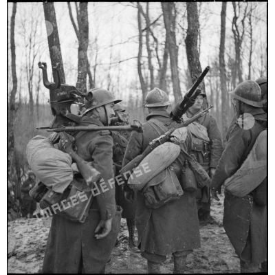 Des soldats sont photographiés de dos dans une forêt du secteur de la 3e armée.