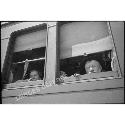 A la fenêtre d'un wagon des évacués saluent de la main en signe de départ.