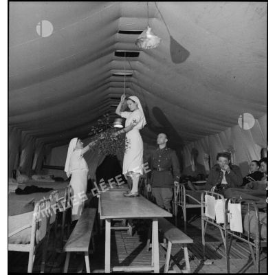 Deux infirmières accrochent du gui sous une tente hôpital dans le secteur de la 4e armée.