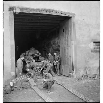 Des mécaniciens réparent le train de roulement d'un char R35 du 5e BCC dans une grange.