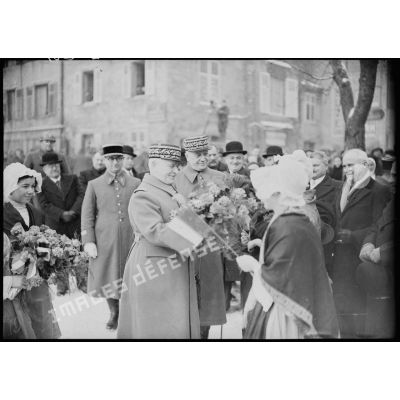 Lors d'une cérémonie militaire des jeunes filles lorraines offrent des fleurs aux généraux Georges et Réquin.