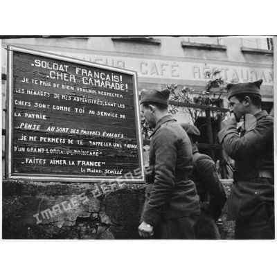 Des soldats de la 4e armée lisent une affiche demandant de respecter les biens civils d'un village lorrain évacué.