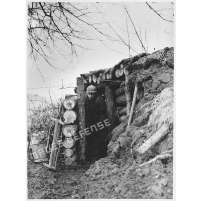 Un soldat de la 4e armée sort d'un abri fortifié de rondins de bois.