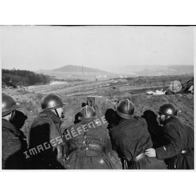 Derrière un talus de terre des soldats de la 4e armée observent le terrain à la binoculaire.