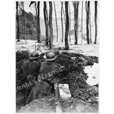 Deux soldats de la 4e armée sont photographiés de dos dans un trou de combat avec des grenades défensives.