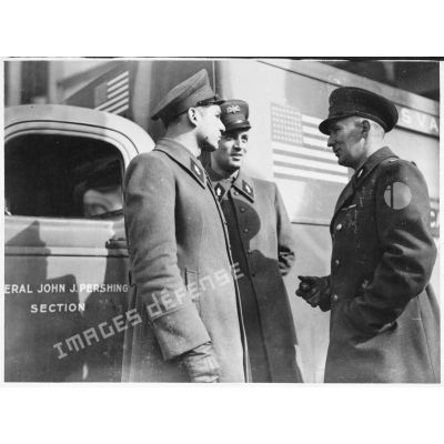 Photographie de groupe de trois volontaires américains de la 1re SSVA (general John J. Pershing) avec en arrière-plan une ambulance.