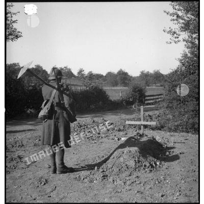 Un soldat de la 4e armée se tient debout devant une tombe.