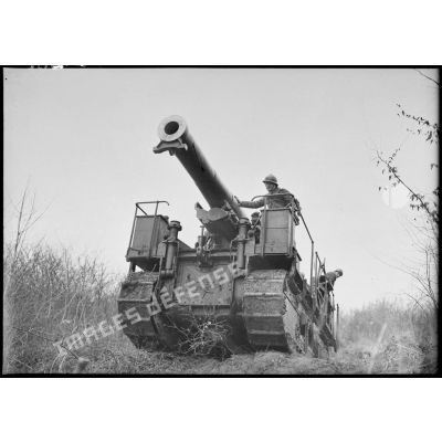 Un canon de 194 GPF sur affût chenillé franchit une butte près d'un bois dans le secteur de la 4e armée.