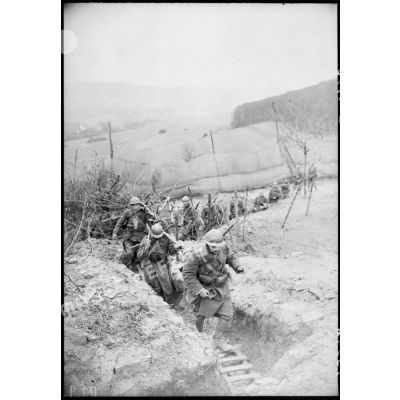 Des fantassins d'une section de mitrailleuses marchent dans un boyau dans le secteur de la 4e armée.