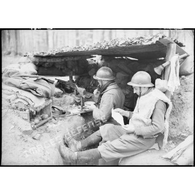 Deux soldats de la 4e armée qui servent un FM 24/29 dans un poste de combat lisent du courrier.