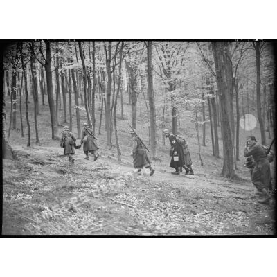 Des soldats de la 4e armée et un aumônier marchent en forêt.