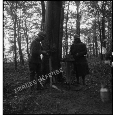 Dans un bois deux soldats de 4e armée préparent un repas sur un poêle.