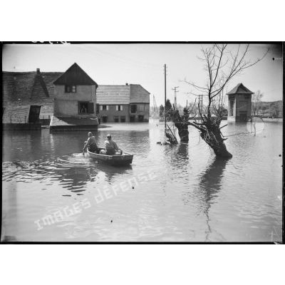Des soldats de la 4e armée se déplacent en barque au milieu d'un village lorrain inondé. (Puttelange-aux-Lacs).
