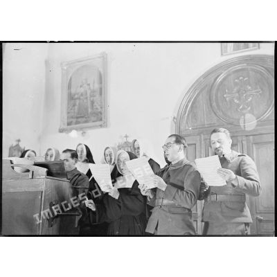 Photographie de groupe de soldats de la 4e armée et de religieuses qui chantent dans une chorale.