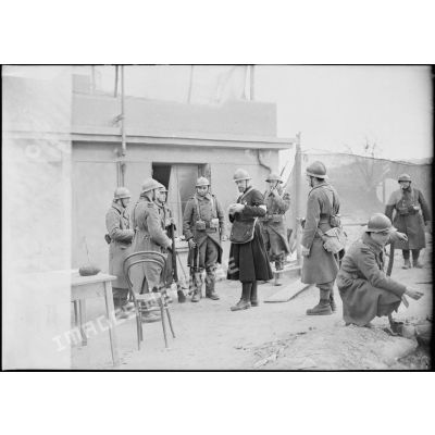 Un aumônier de la 4e armée rend visite à des soldats, il discute avec eux près d'une casemate bétonnée.