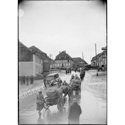 Un convoi hippomobile traverse un village.