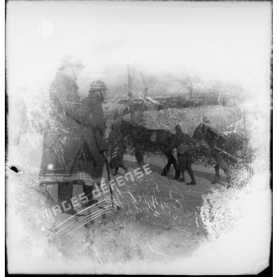 Un officier de la 4e armée regarde passer un convoi de ravitaillement dans la neige.