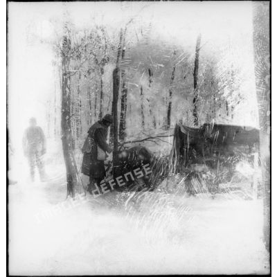 En forêt, des soldats de la 4e armée se tiennent près de toiles de tentes recouvertes de neige.