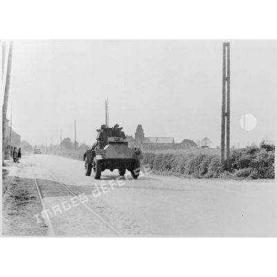 Plan général de face d'une automitrailleuse Guy Mk I du 12e lanciers britannique qui roule sur une route près de Thisnes le 10 mai 1940 à 14 heures.