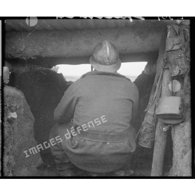 Un soldat de la 5e armée est photographié de dos en plan moyen dans un poste de tir.