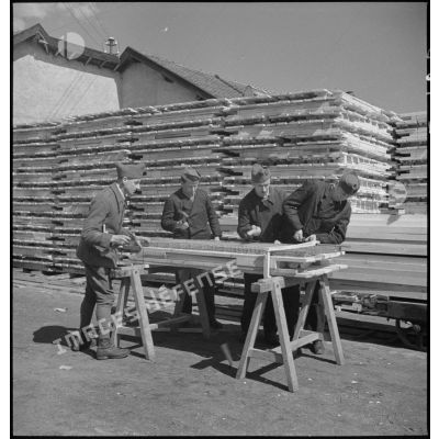 A l'extérieur de l'atelier des soldats de la 5e armée assemblent des cadres de lits en bois.
